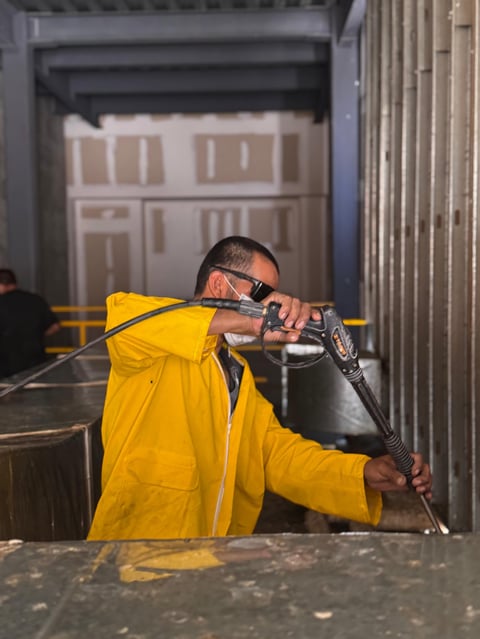 Man in yellow jacket aiming paintball gun indoors at an indoor shooting range